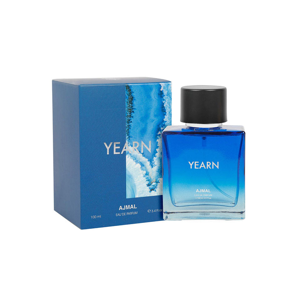 A blue gradient bottle of AJMAL YEARN EAU DE PARFUM 100ML FOR MEN with a black cap stands beside its matching blue box, both featuring white text and wave designs. The bottle holds 100 ml of fragrance for men.