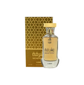 A clear glass AJMAL MOSHRIQA EAU DE PARFUM FOR MEN & WOMEN bottle with a gold cap stands before a gold and brown patterned box displaying Arabic script and matching unisex perfume branding.