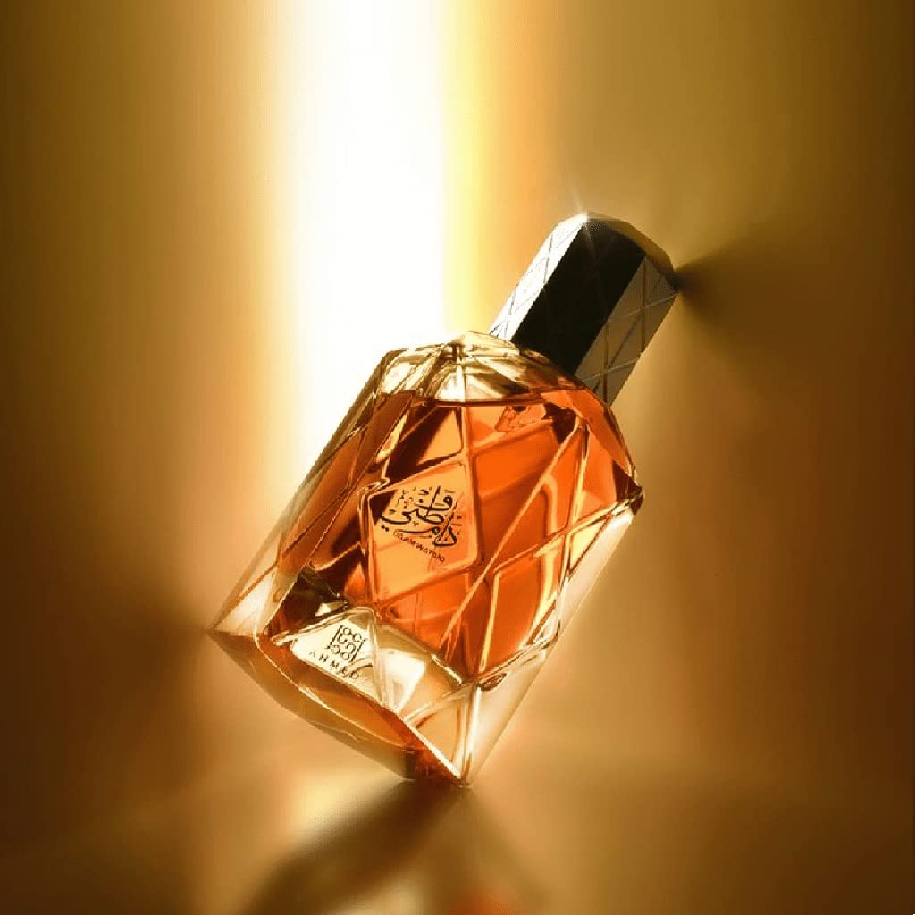 A faceted glass bottle of BIN SHAIKH BY AHMED AL MAGHRIBI EAU DE PARFUM 90ML FOR MEN & WOMEN, filled with amber liquid, lies on its side against a golden background. Elegant Arabic calligraphy adorns the front, reflecting sophistication and luxury.