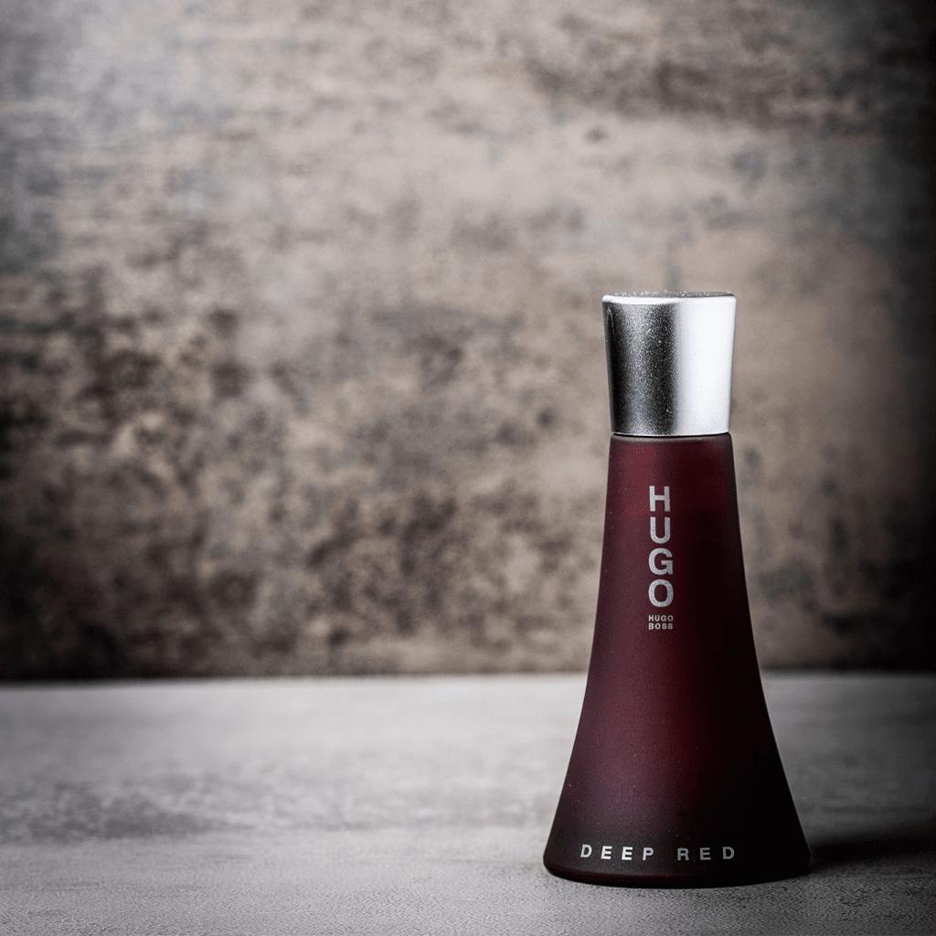 Bottle of Boss HUGO Deep Red Eau De Parfum for women, featuring a sleek red and black design, 90ml size on a white background.