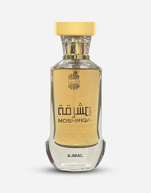 A clear glass bottle of AJMAL MOSHRIQA EAU DE PARFUM FOR MEN & WOMEN holds golden liquid, labeled MOSHRIQA in English and Arabic, with AJMAL at the base. This elegant unisex perfume has a gold cap and a modern design.