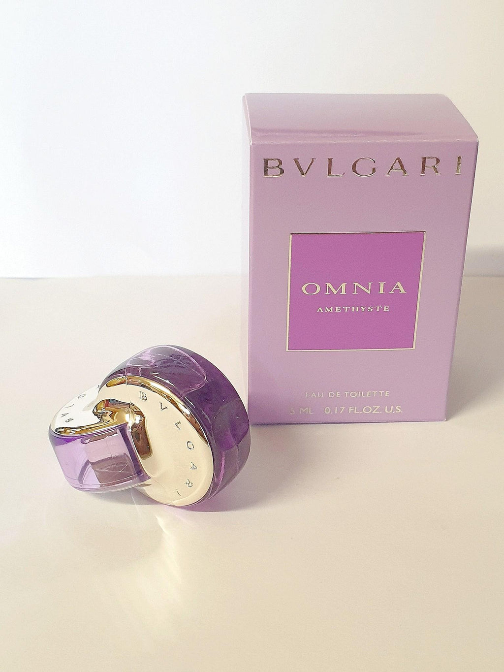 Miniature Bvlgari Omnia Eau De Toilette bottle, 5ml, with sleek design and purple accents, ideal for travel or gift.
